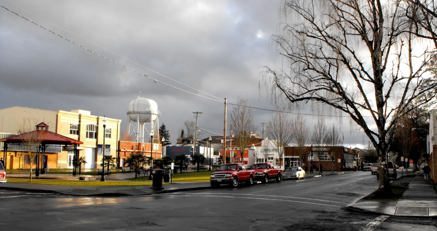 The downtown square in Woodburn, Oregon, with the city water tower behind the storefronts on a wet winter afternoon
